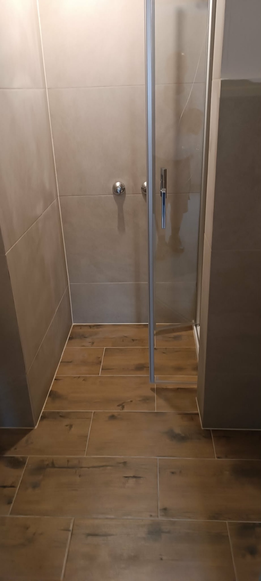 Begehbare Dusche mit grauen Wandfliesen und Bodenfliesen in Holzoptik